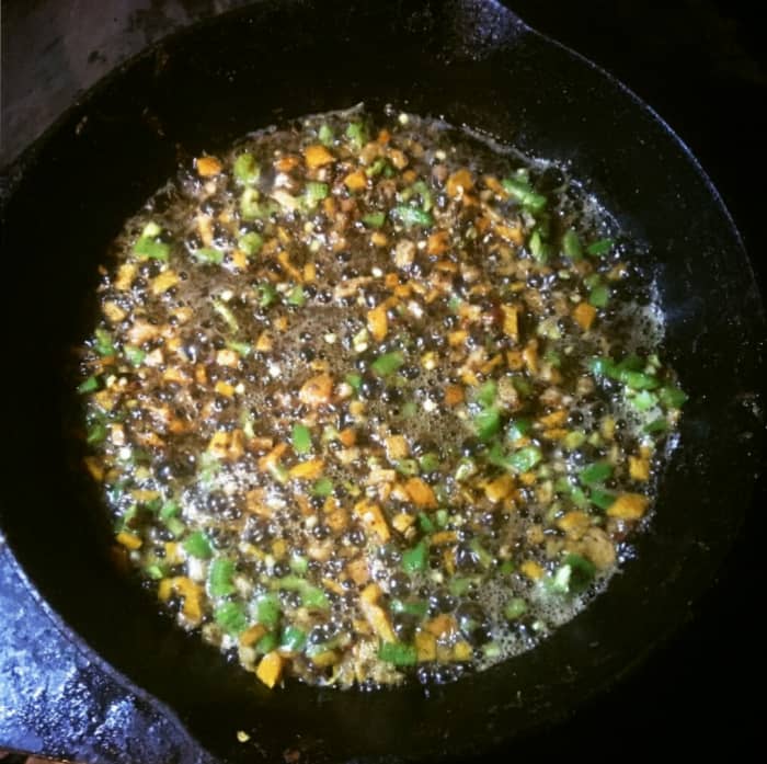 The spices, orange, and peppers simmer briefly by themselves in butter. The heat must be low, or they will burn. A minute or two of cooking is enough; you only want to blend flavors.