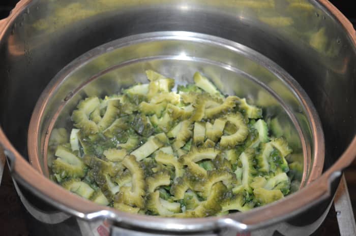 Cook the bitter gourd in a pressure cooker up to 2 whistles and simmer for 2 to 3 minutes. There's no need to add water to the bitter gourd.