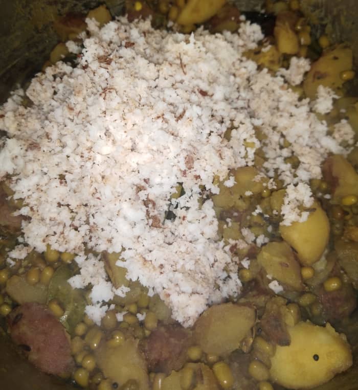 Once everything is cooked and tender and the water dries up completely, lower the flame and add fresh grated coconut.