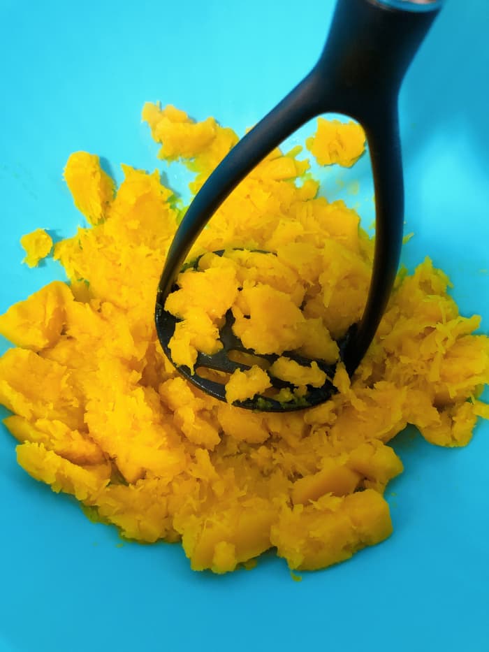 Strain the water from the pot. Throw the pumpkin into a large mixing bowl. Use a masher to mash the pumpkin.