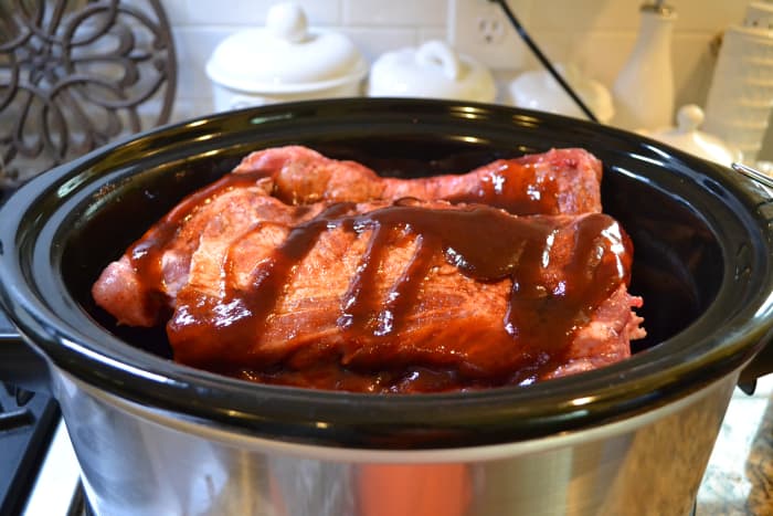 Stack ribs in the crock pot, cutting them in half to fit, if necessary. Drizzle liquid smoke and barbecue sauce over each rack before stacking another on top.