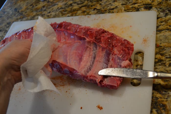 Using a paper towel for grip, pull the membrane, pulling from one end of the rack to the other. Use the butter knife to hold the slippery rib in place as you pull.