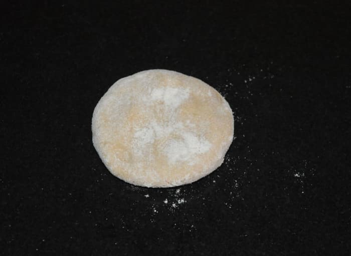 Step four: Gently knead the dough once again. Take a lemon-sized dough portion and shape it like a patty. Make a small disc out of it. Use wheat flour for dusting while rolling.