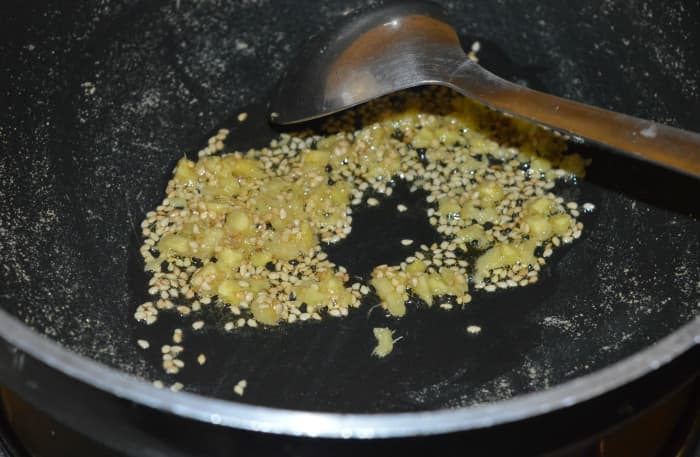 Step three: Heat oil in a deep-bottomed pan. Add nigella seeds or sesame seeds and chopped ginger. Saute until the seeds are roasted. Turn off the heat.