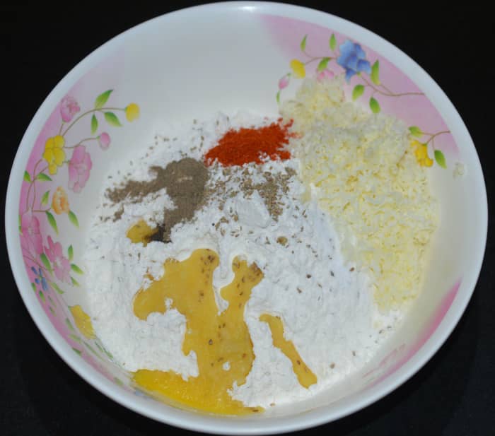Step one: In a mixing bowl, add all-purpose flour, carom seeds, pepper powder, red chili powder, and warm ghee. Knead while adding water to get a firm, pliable, and smooth dough.