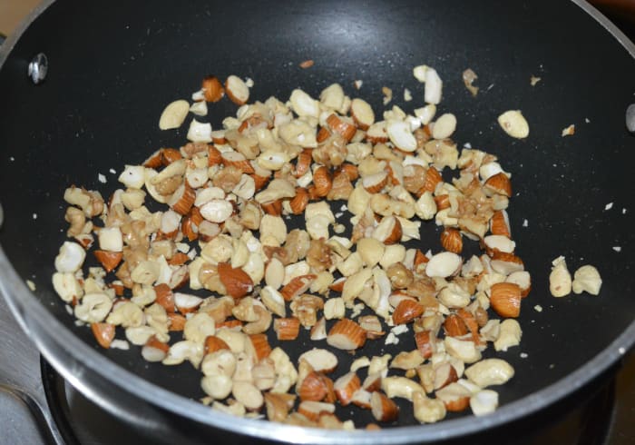 Step two: Heat a very small amount of ghee in a deep-bottomed pan. Saute chopped almonds, cashews, and walnuts. Continue to saute until they become crispy. Transfer the nuts to a plate.