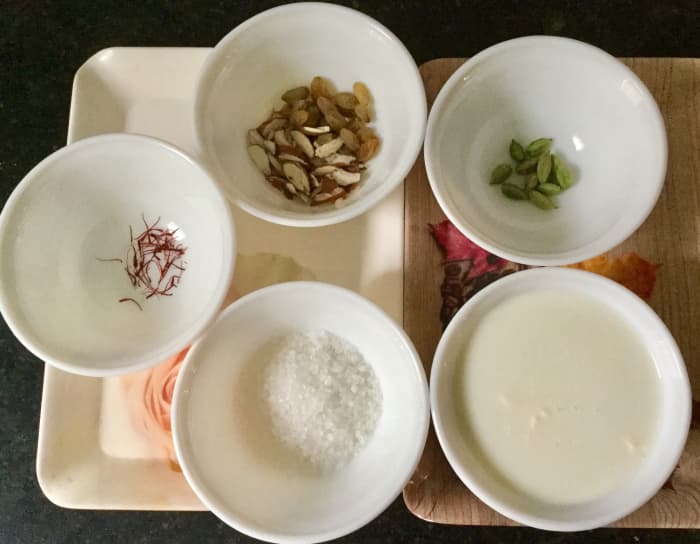 Ingredients for kesar elaichi kulfi: milk, sugar, saffron, cardamom, chopped nuts.