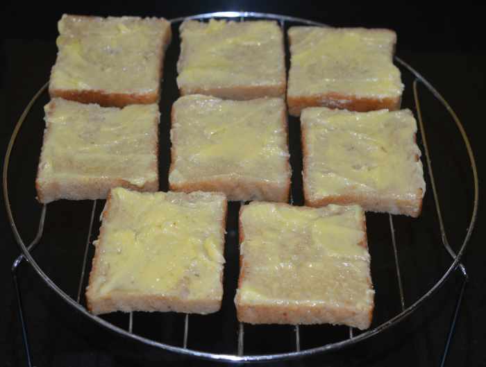 Step two: Take the grill stand out. Apply butter on the top side of all the slices. Arrange them on the grill stand.