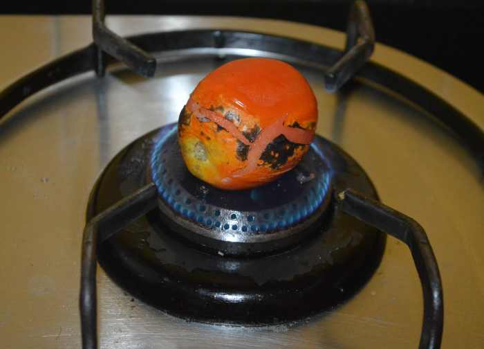 Step one: Roast the tomatoes on a gas stove.