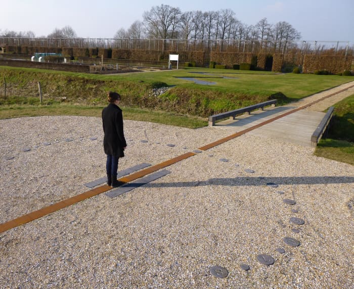 The woman acts as a gnomon and casts a shadow on one of the hour lines. The hour that you derive from this is solar time and must be converted to local time.