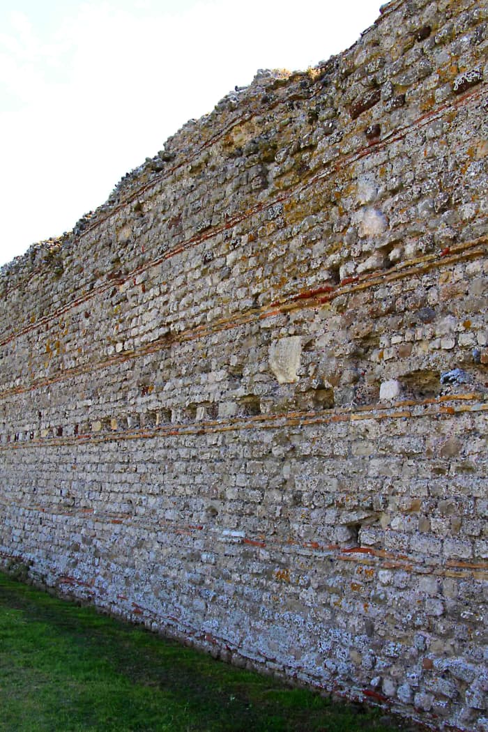 The characteristically imposing Roman wall on the north side of Rutupiae, built of flint stone, concrete and tiles, c 273 AD and still largely intact today