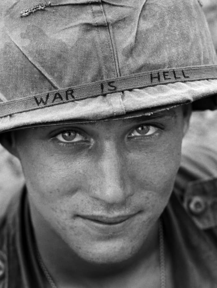 An unidentified American soldier wears a hand-lettered slogan on his helmet, June 1965. The soldier was serving with the 173rd Airborne Brigade on defense duty at the Phuoc Vinh airfield.