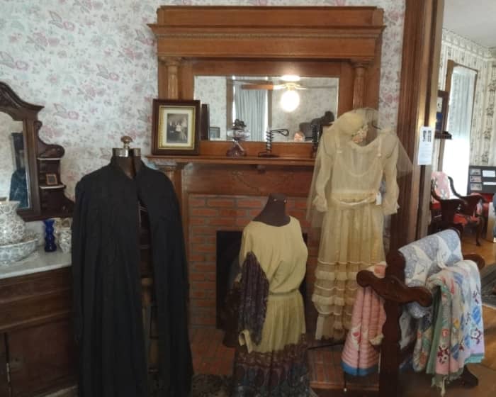 The fireplace shown is on the backside shared wall of the front parlor. On display are costumes worn during the era.