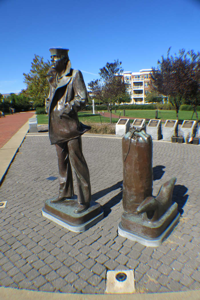 Statute of Lone Sailor in Jacket with collar up and Duffel Bag at his side ready to go to Sea