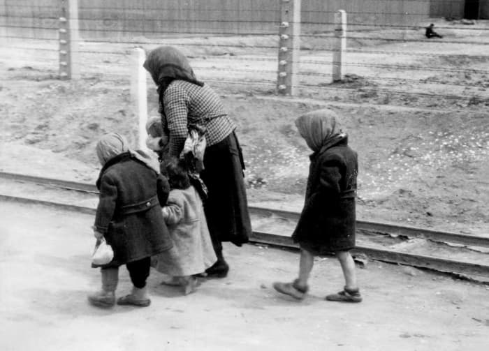 Hunched over and beaten down, a woman and her children in Auschwitz, perhaps on their way to the gas chambers.