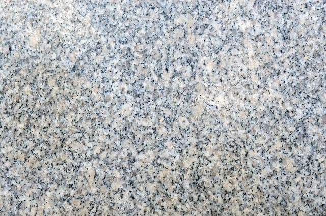 This photograph shows the mineral composition of a slab of granite; the white areas are quartz, the buff-colored parts are feldspar, and the black specs are mica.
