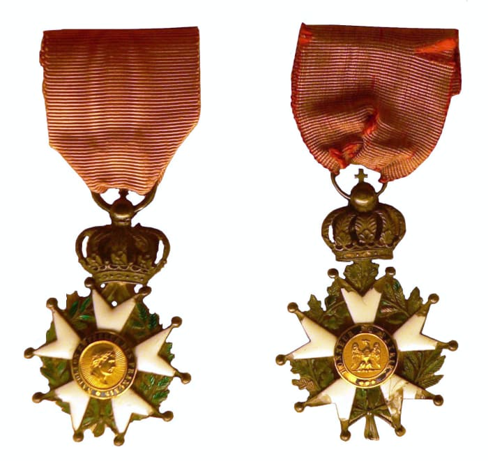 Late Empire Légionnaire insignia: the front features Napoleon's profile and the rear, the imperial Eagle. An imperial crown joins the cross and the ribbon.