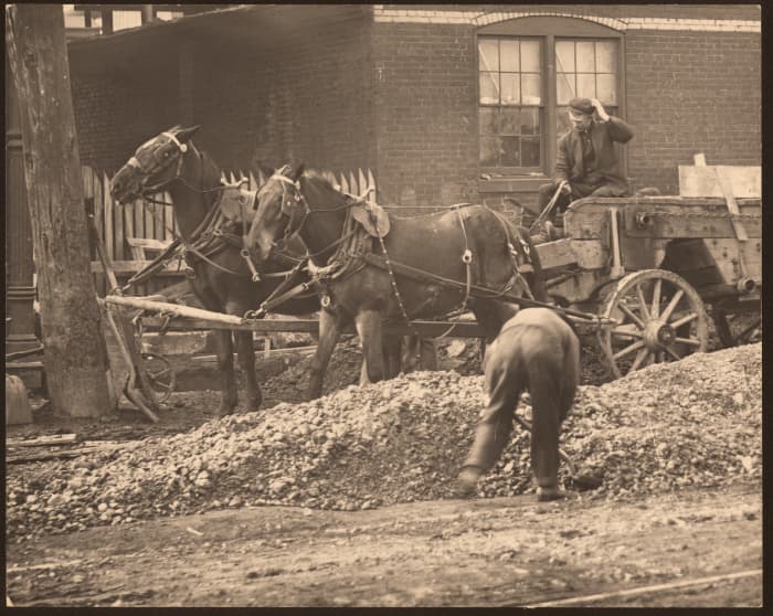 Horse drawn wagon at an unknown street construction site.