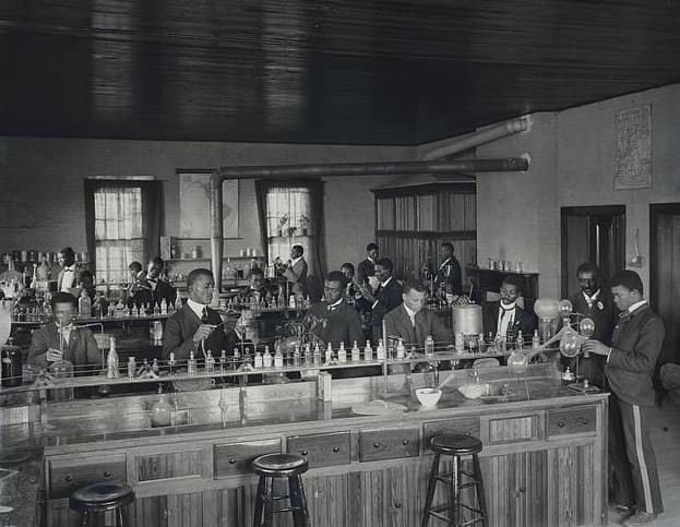 Chemistry laboratory at Tuskegee Institute, circa 1902. Carver stands second from right, facing front.
