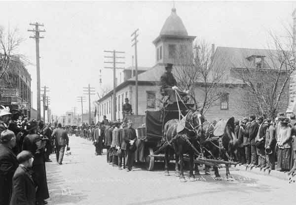 "A funeral for twenty one people who died when state militia attacked and burned a tent colony set up by striking coal miners."