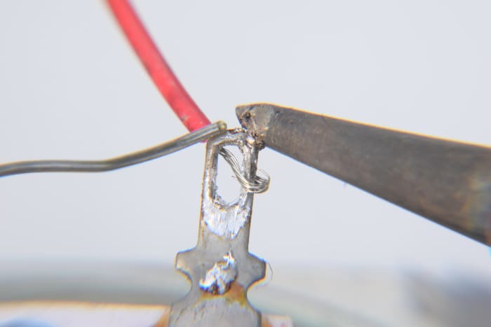 Tin the iron tip and hold it against the tag. After a couple of seconds the tag will be hot enough to melt the solder. Touch the solder wire off the tag, not the iron.