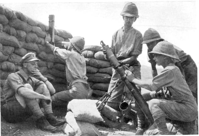 Photograph of British troops loading Stokes mortar, in a sandbagged emplacement. Clothing and headgear indicates somewhere in the Middle East. circa. 1916-1917