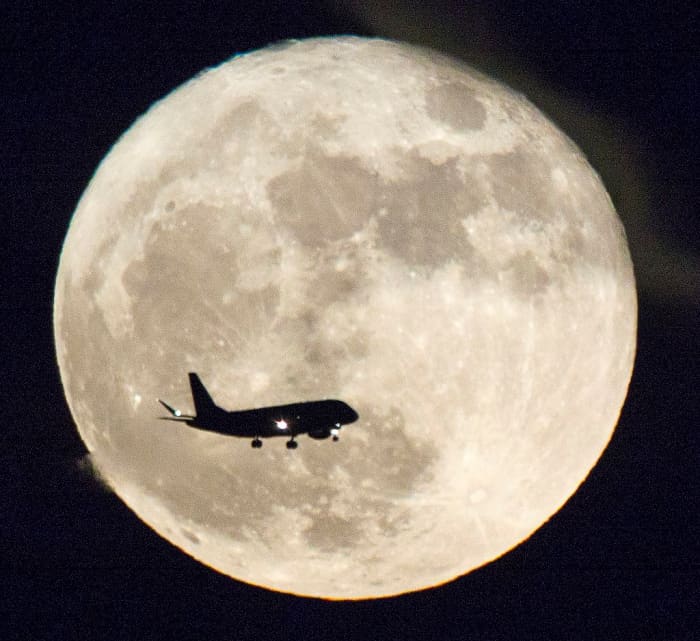 A jetliner is silhouetted against a Supermoon in Austin, Texas on November 14 in 2016, photo by Jay Godwin