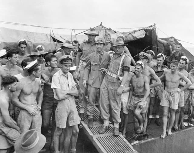 The sadistic manager of a POW camp in Indonesia, Ikeuchi Masakiyo, is escorted by Australian military police. Masakiyo was executed for war crimes in 1947.