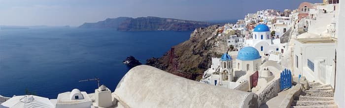 The whitewashed architecture of the Greek Islands attracts visitors from all over the world. Less noticeable is the great body of water on the left, which is actually an ancient caldera