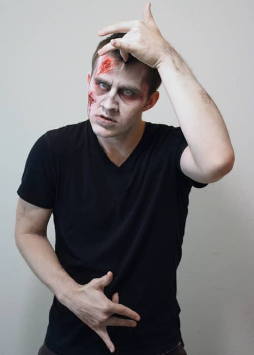 The middle finger of the right hand is held to the abdomen and the middle finger of left hand is held to the forehead.