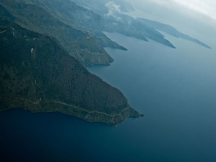 The southeast shore of Lake Toba, Indonesia; it is the remnant of a vast caldera blasted out of the surface about 73,000 years ago. The debris may have caused years of volcanic "winter," killing many creatures, including most early humans.