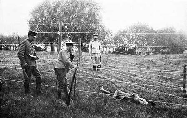 WW1: In the foreground soldiers of a Dutch border patrol. On the other side of the fence a German soldier. In between them a body lying under the deadly wire. To remove bodies the current had to be switched off.
