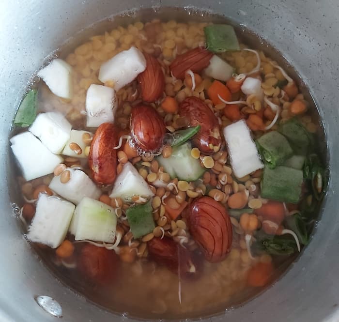Transfer all chopped vegetables, sprouts, and lentils to the cooker. Add enough water and salt to taste.