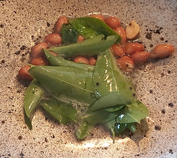 In a frying pan, heat 1–2 teaspoons of oil. Splutter the mustard seeds, add 1–2 tablespoons of peanuts, and fry till golden and crisp. Add fresh curry leaves, fry, and switch off the heat.