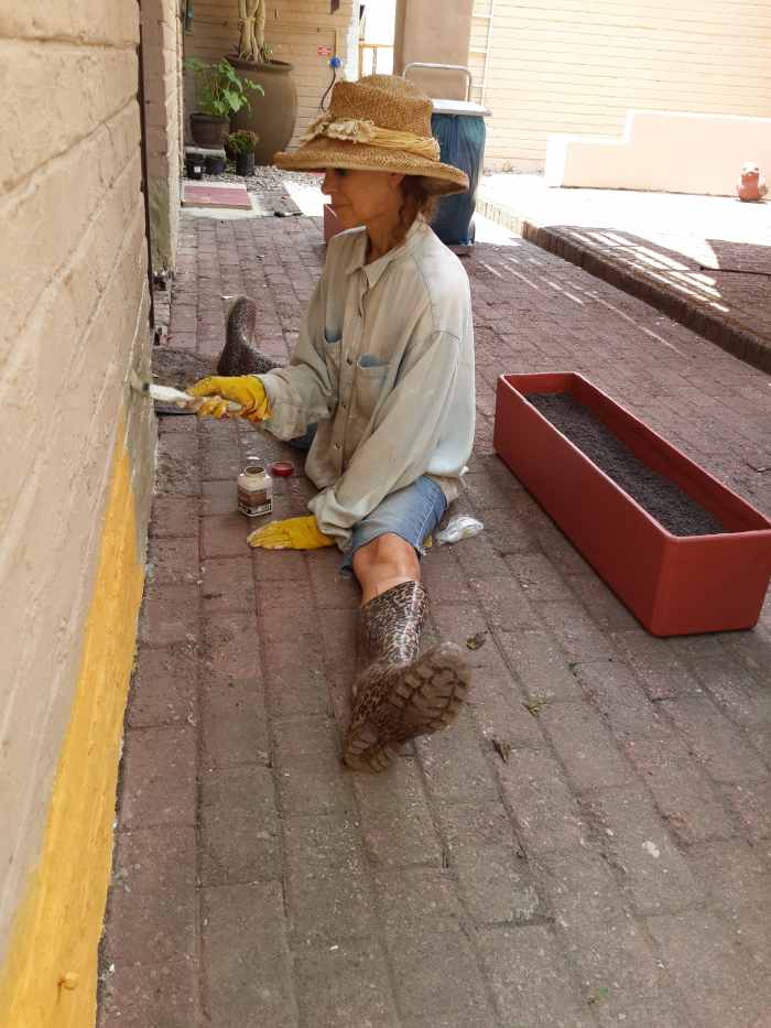 Charmaine, age 62, painting the wall. Every opportunity is used to get some exercise - in this case doing the splits! Sedgefield, South Africa.