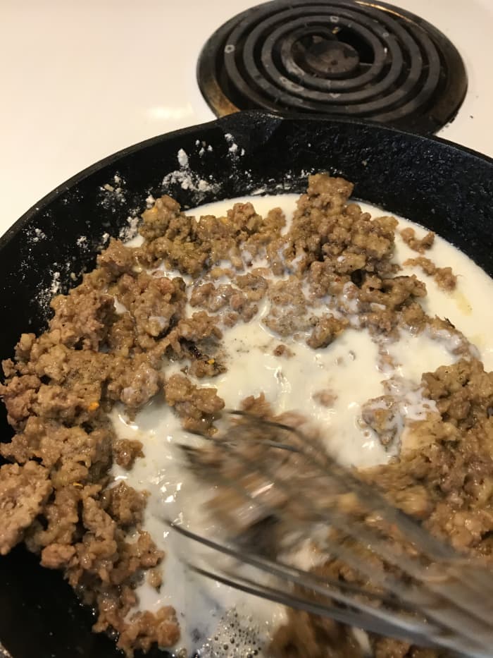 You can warm the milk before you add it to prevent lumps, or save the dishes and just go slowly. Add a little at first, whisking well to make sure it's smooth.