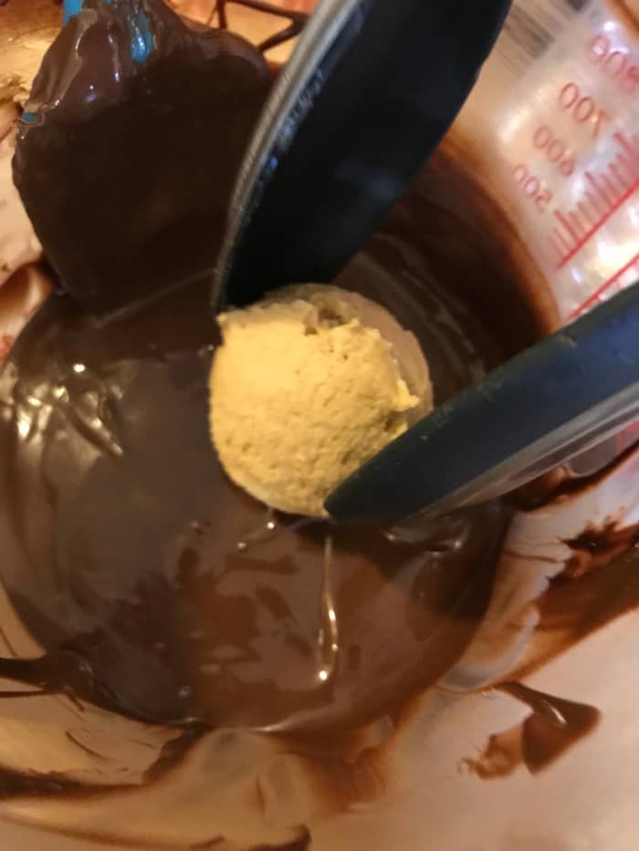 Dip the chilled peanut butter balls into the melted chocolate about halfway, or maybe a bit more. You want to leave a good portion of the candy exposed, to get the classic dark and light brown look.