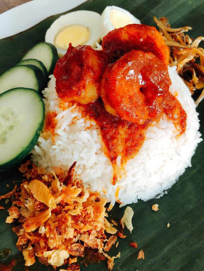 Nasi Lemak. There are a variety of side dishes served on top of the nasi lemak: fried anchovies, sambal udang, fried fish, hard-boiled egg, and fresh sliced cucumber.
