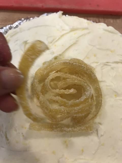 Once the crumb coat has chilled, frost the entire cake with the remaining lemon buttercream. Garnish with candied lemon peel for a beautiful presentation!