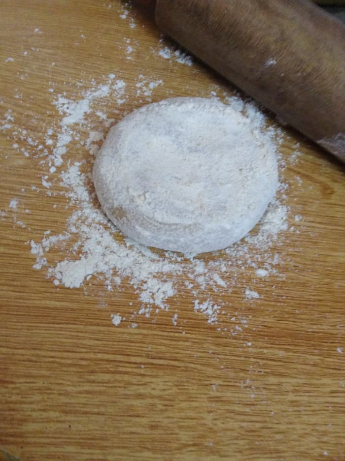 Cover the ball of dough with dry flour while flattening it. This will prevent it from sticking on the wooden board.