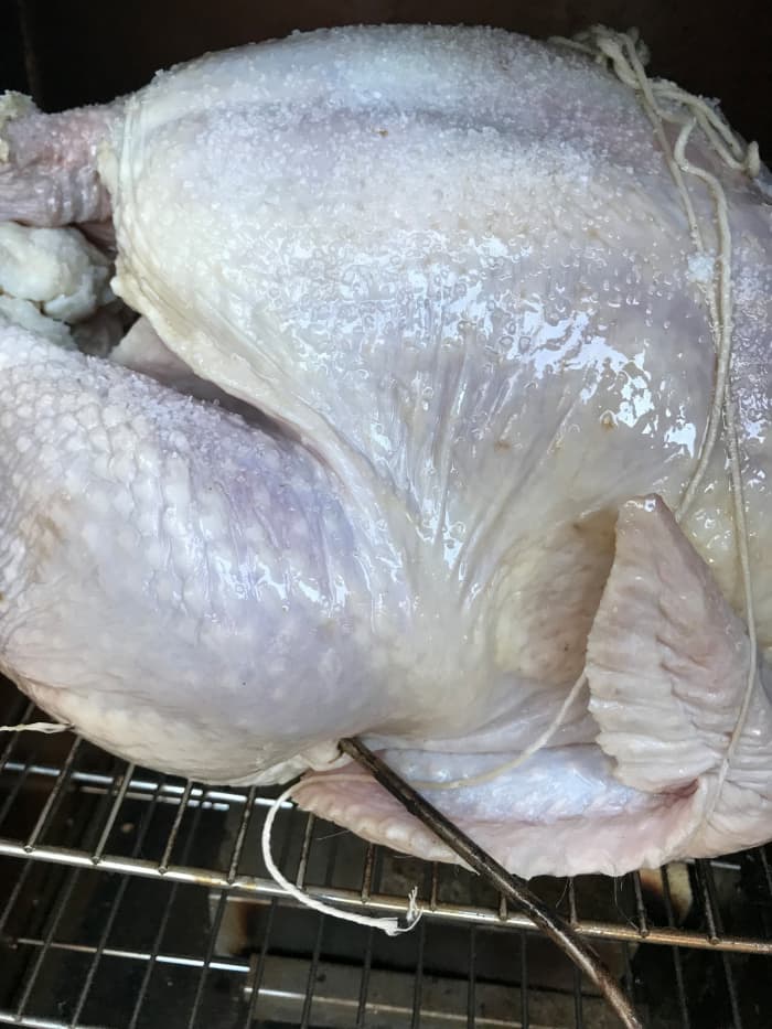Set a meat thermometer into the thickest part of the thigh - called the oyster. You're going to aim for an internal temp of 165F. Turn your smoker to 225F, add hickory chips, sprinkle with kosher salt, and just let it be for a couple of hours.