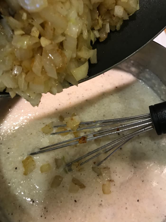 Stir the sauteed onions and garlic into the cooked grits. This starts building the incredible flavors of the casserole.