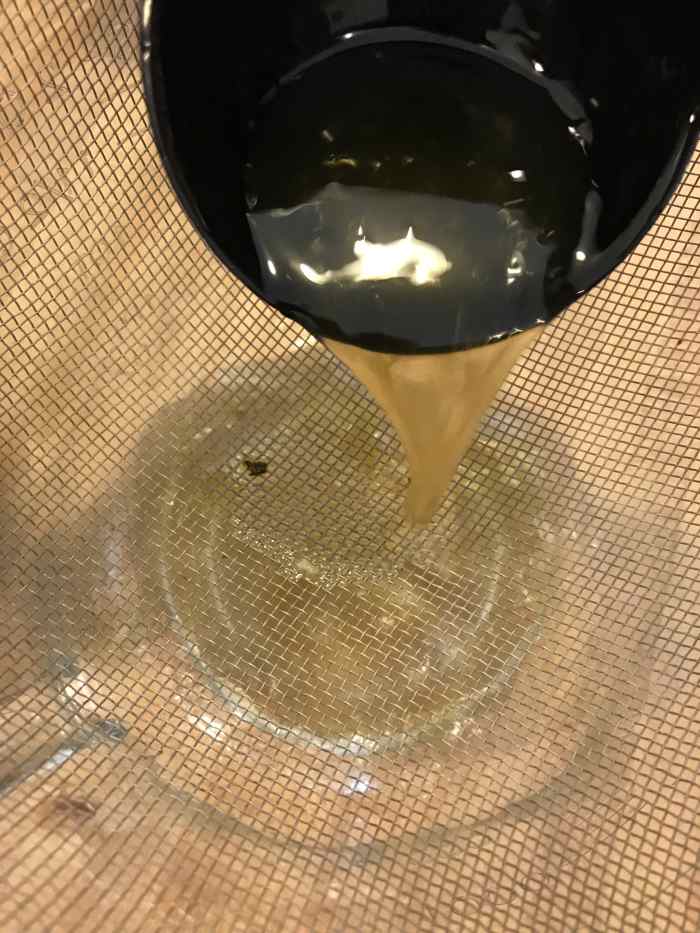 I find it easiest to strain the finished broth by placing a fine mesh strainer over a large container. Ladle it at first, until you can remove most of the large solids. That makes the big pot easier to handle.