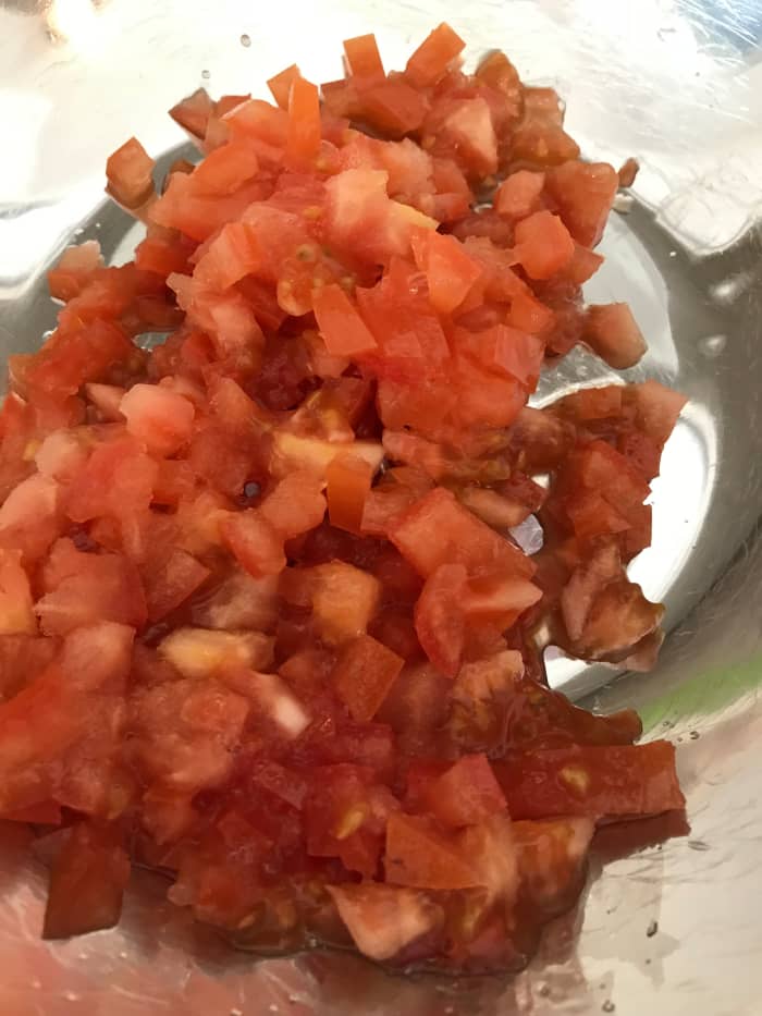 I like the texture of fresh Roma tomatoes, and they tend to have a lower moisture content than other varieties, so they 'weep' less in the finished guacamole.