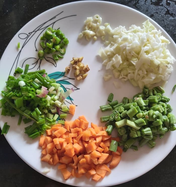 Wash and chop 1/4 cup of carrots, 1/4 cup of french beans, 1/4 cup of cabbage, 1 inch long ginger, 4-5 cloves of garlic and 3-4 tablespoons of spring onion. Keep aside.