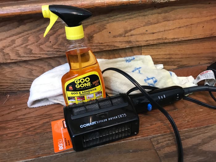 You will need a hair dryer, Goo Gone, an old towel, and a plastic card to use as a scraper to remove a vinyl dealership logo sticker from the back of your new car.