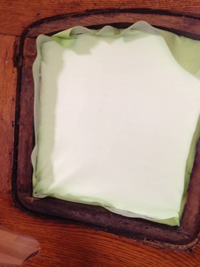 The back-rest of this chair is now closed off with the back piece of fabric, held in place with staples. The padding will fit in this opening and then be covered by more fabric.