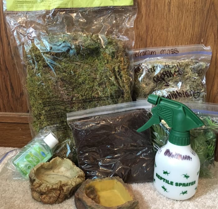 Example of supplies for a reptile or amphibian: moss, soil substrate, misting bottle, dishes, hand sanitizer (for salmonella risk). Only things missing are travel cage, heating element, and food. Supplies required will depend on species, of course.