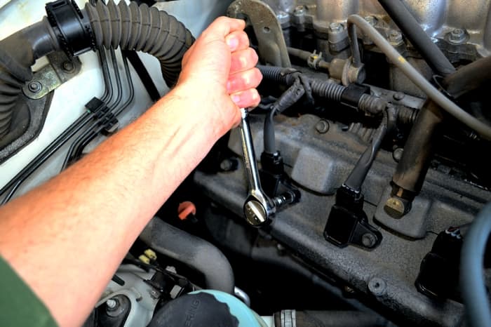 Use the 10mm socket to remove the hex nut holding on one of the plug coils. Turn toward the left to loosen.