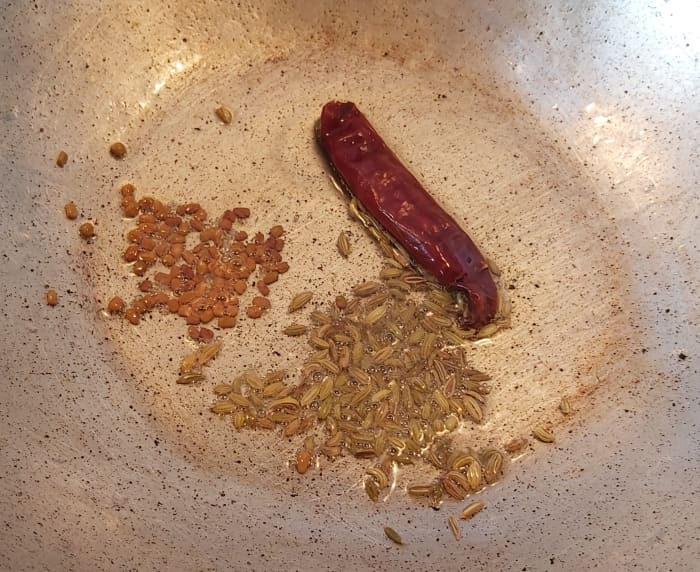 In a frying pan, heat 1 to 2 tablespoons of oil, add 1/2 teaspoon of fenugreek seeds, 1 teaspoon of fennel seeds and 1 to 2 red chilies (or more as per your spice preference).